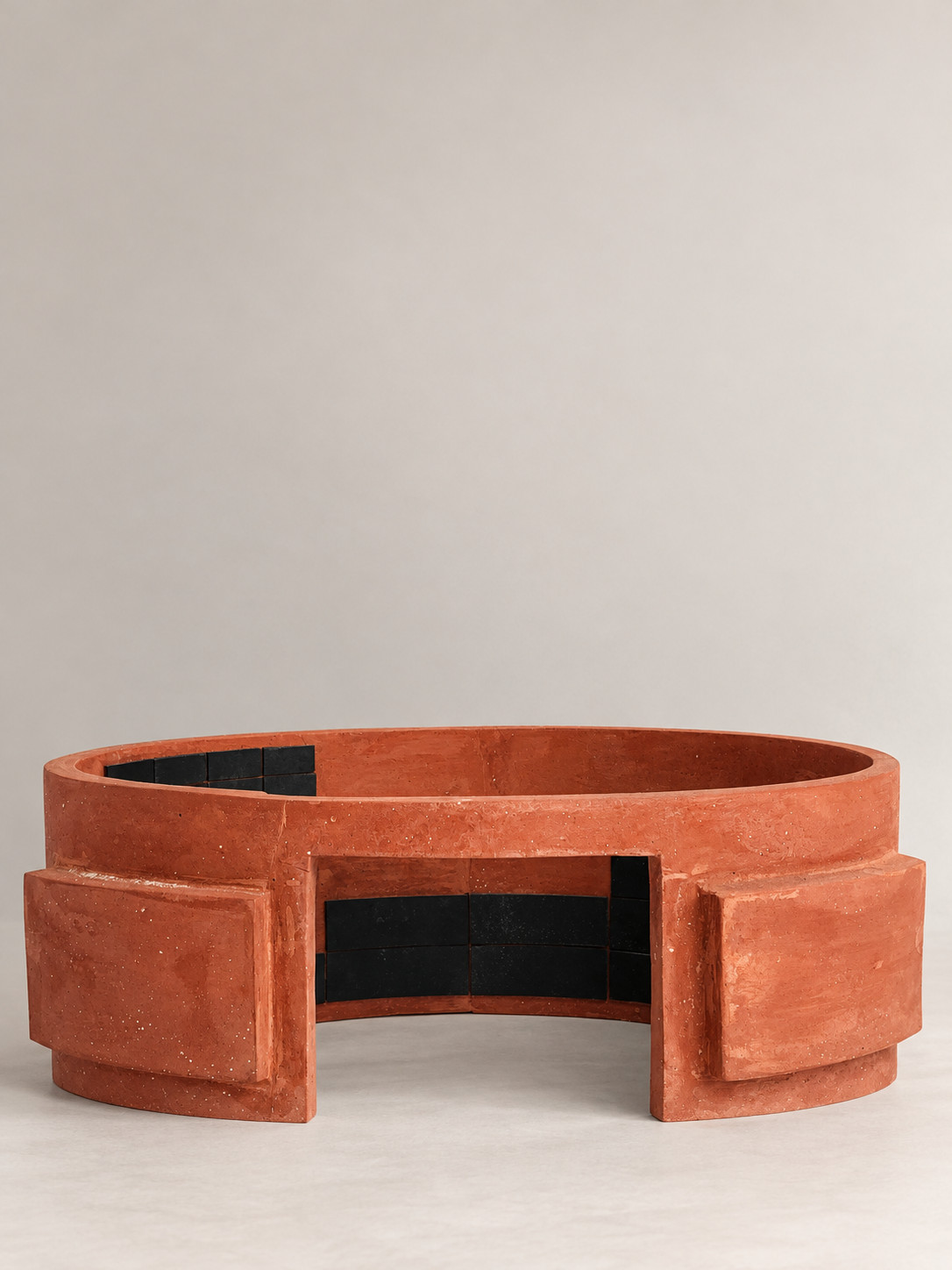Anillo de barro rojo con aberturas y piezas negras, vista frontal